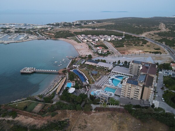 An aerial view of a coastal resort with a marina, swimming pools, and a beach. - Laur Hotels Experience & Elegance (Didim)