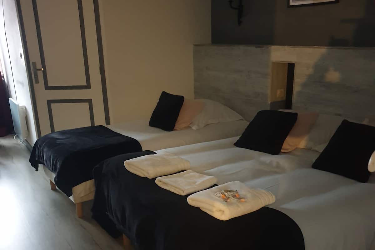 A hotel room with two beds, a wooden floor, a door, and a framed picture on the wall.