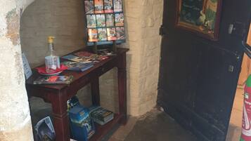 A narrow hallway with a wooden table displaying brochures and a bottle of hand sanitizer. A chalkboard menu hangs on the wall to the right.