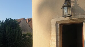 Een balkon met een houten bankje, een lantaarn en een vat.