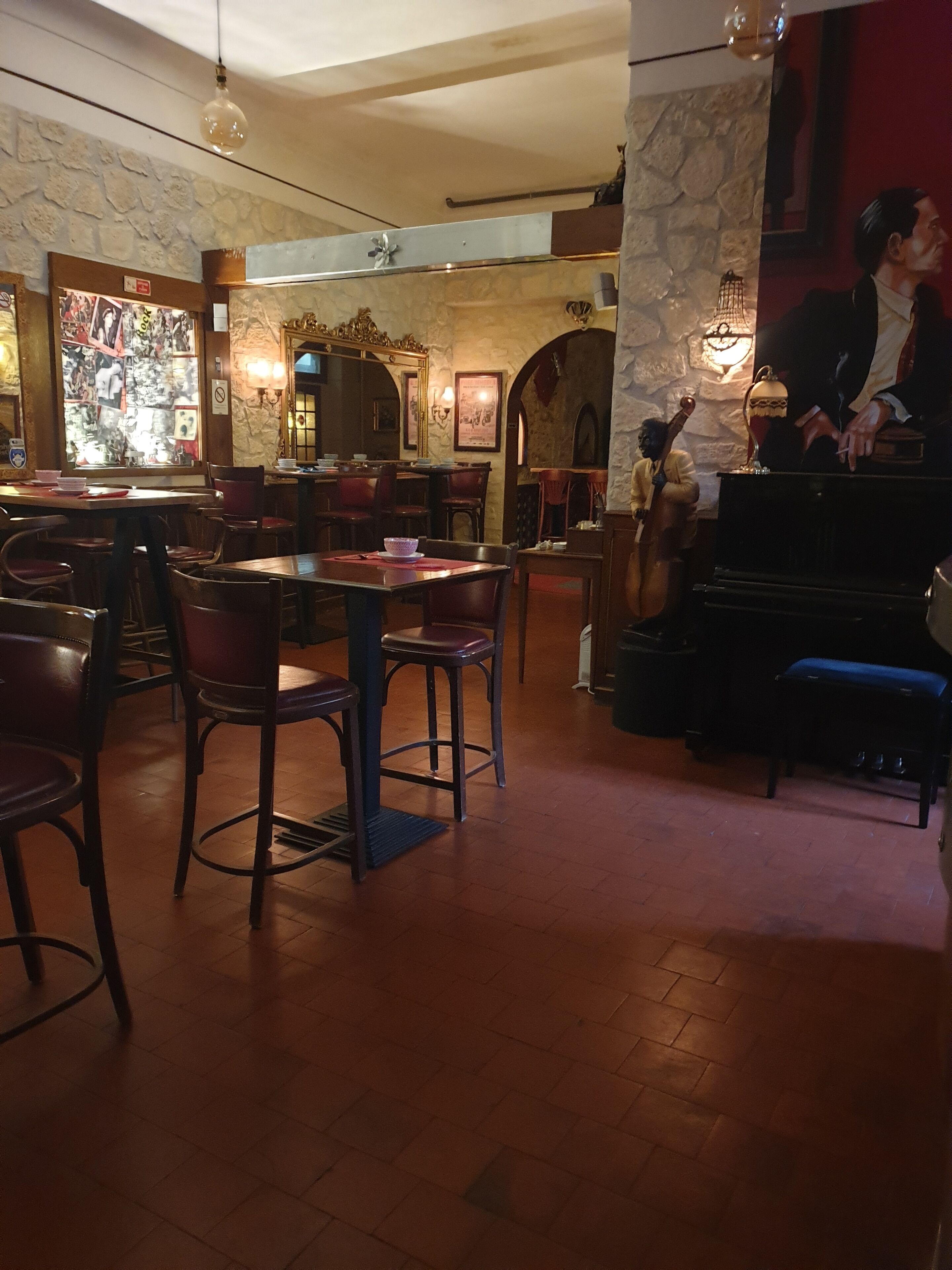 Un restaurante con mesas y sillas de madera, paredes de piedra y un piano.