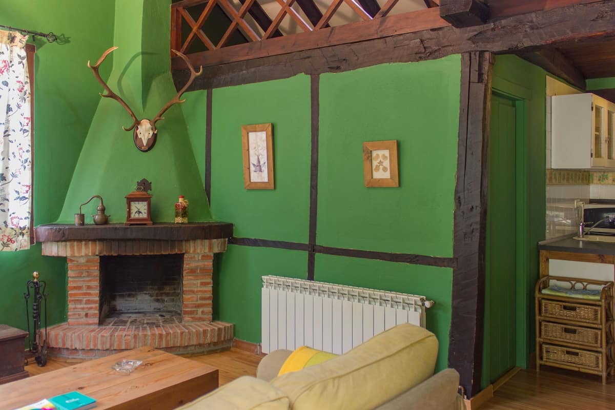 A cozy living room with a brick fireplace, green walls, and a wooden ceiling.