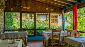 An indoor dining area with wooden beams, large windows, and tables set for dining. - Viviendas Rurales El Covaju (Cabezon de Liebana)