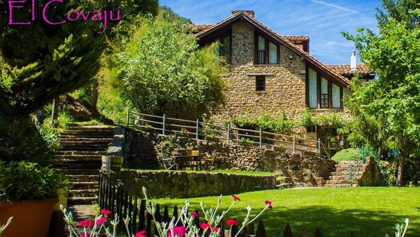 A stone house with a stone staircase leading to a wooden deck. - Viviendas Rurales El Covaju (Cabezon de Liebana)
