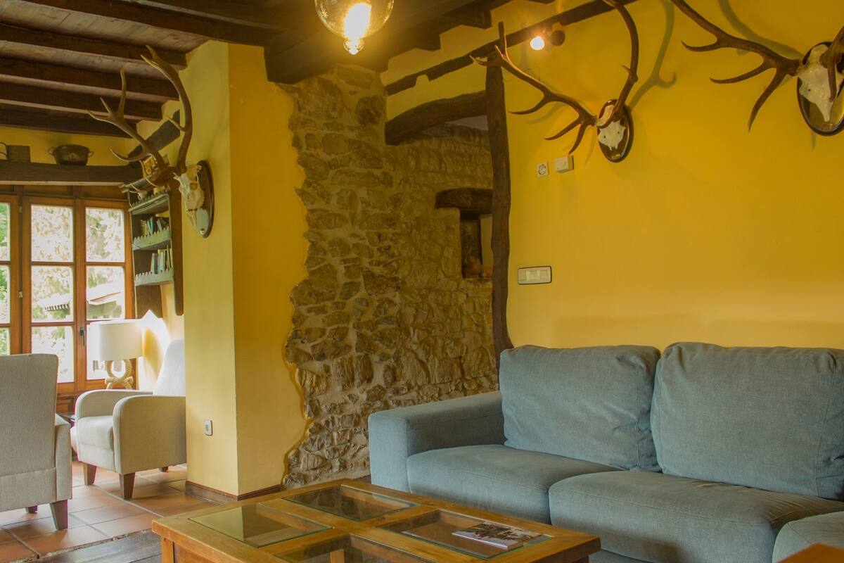 A cozy living room with a stone wall, a blue sofa, and a wooden coffee table.
