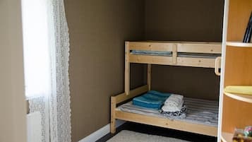 Cozy retreat with a bunk bed, shelf unit, and window with lace curtains.