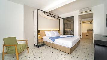 Una habitación de hotel moderna con una cama grande, una silla verde y un vestidor.