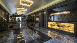 A reception area with a marble floor, modern chandeliers, and a reception desk labeled "RECEPTION". - Hotel Karbelsun (Fethiye)