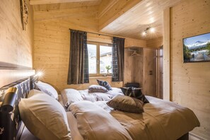 Ein Schlafzimmer einer Holzhütte mit einem Bett, einem Kleiderschrank und einem Fenster mit Vorhängen.