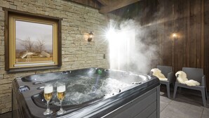 A hot tub with two glasses of champagne, a framed picture on the wall, and two chairs with fluffy cushions. - Narzenhof Chalets - Familien & Luxus Apartments (Sankt Johann in Tirol)