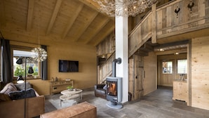 A cozy wooden interior with a central fireplace, a sofa, a coffee table, and a bench. - Narzenhof Chalets - Familien & Luxus Apartments (Sankt Johann in Tirol)