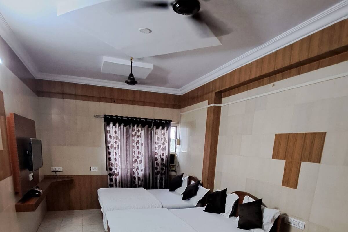Ein Hotelzimmer mit einem großen Bett, einem Schreibtisch, einem Sessel, einem Deckenventilator und einem Fernseher.