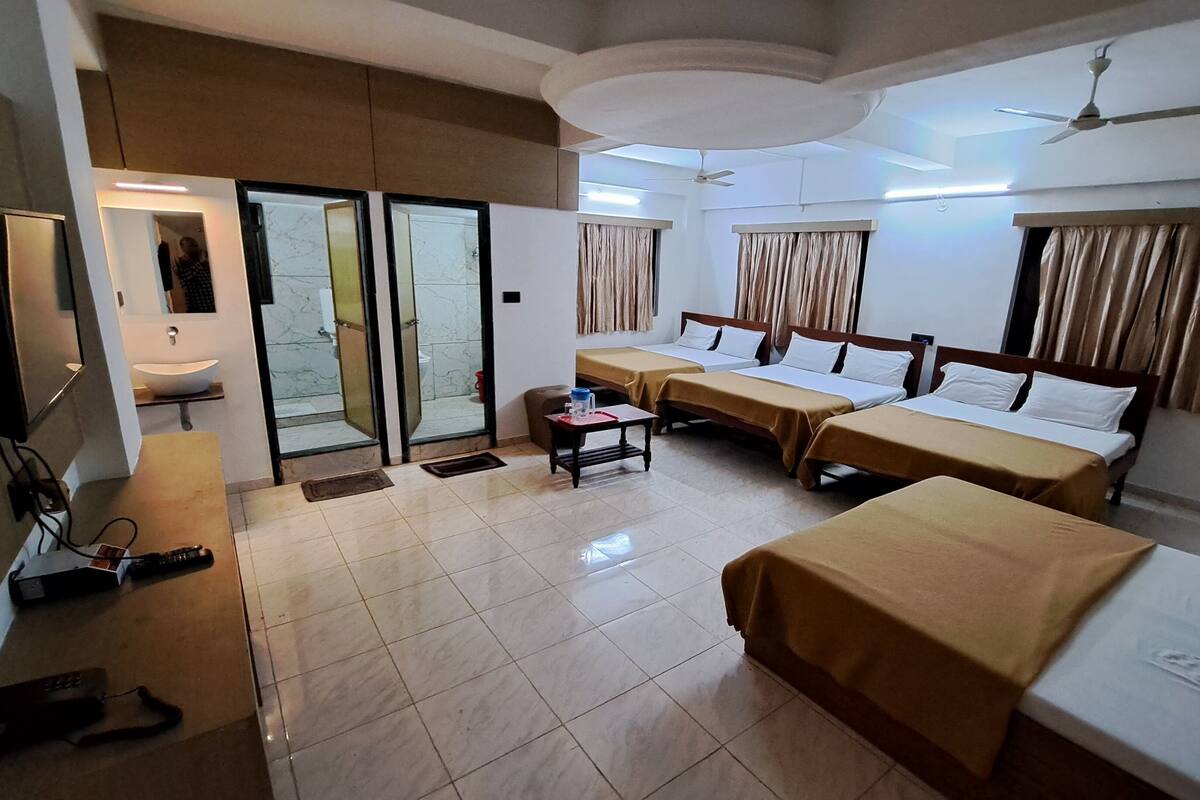 Ein Hotelzimmer mit zwei Einzelbetten, einem kleinen Tisch, einem Fernseher und einem Badezimmer mit Waschbecken und Toilette.