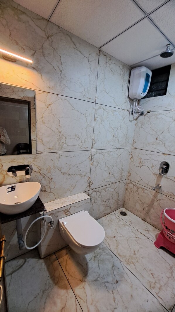 A bathroom with a marble floor, a sink, a toilet, and a shower.