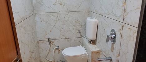 Un baño con inodoro, lavamanos, ducha y secador de manos.