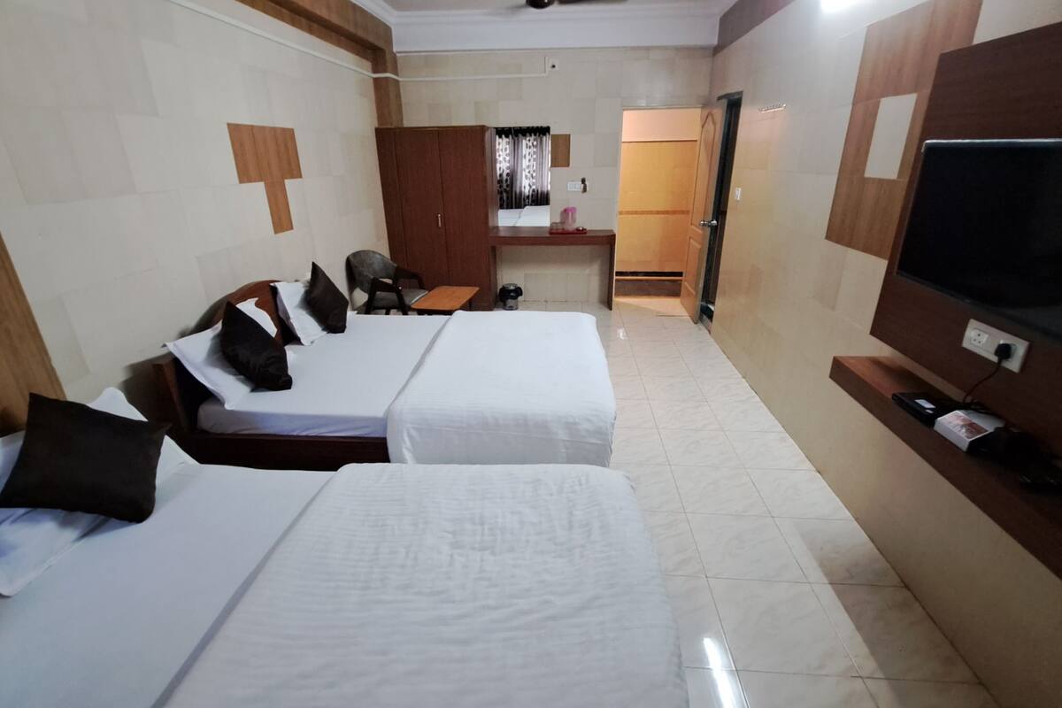 Ein Hotelzimmer mit zwei Betten, einem Fernseher, einem Schreibtisch und einer Küchenzeile.