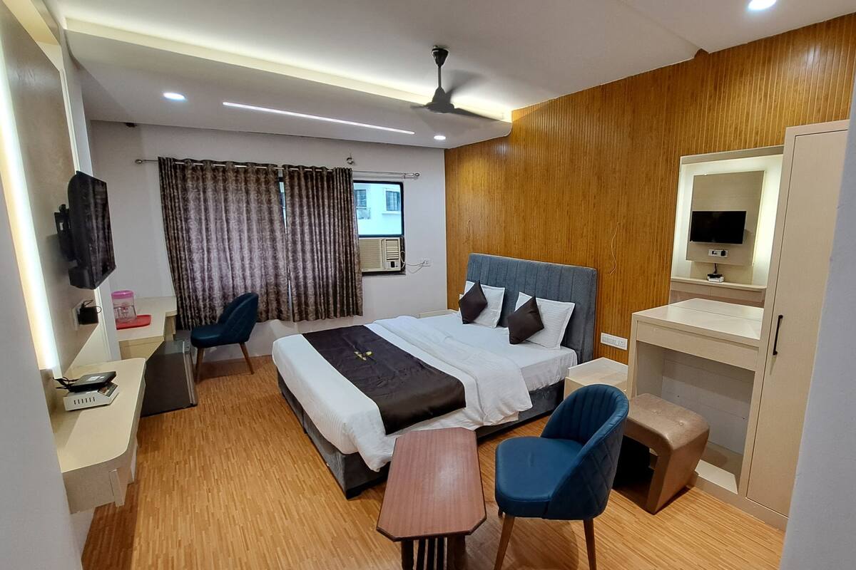 Ein Hotelzimmer mit Bett, Schreibtisch, Stuhl, einem kleinen Tisch, einem Fernseher und einem Kleiderschrank.