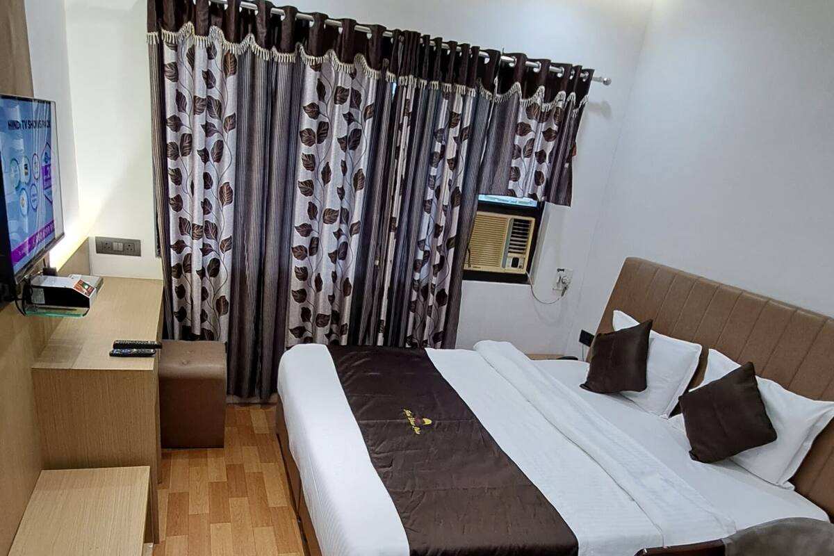 Ein modernes Hotelzimmer mit Bett, Nachttischen, Fernseher und Deckenventilator.