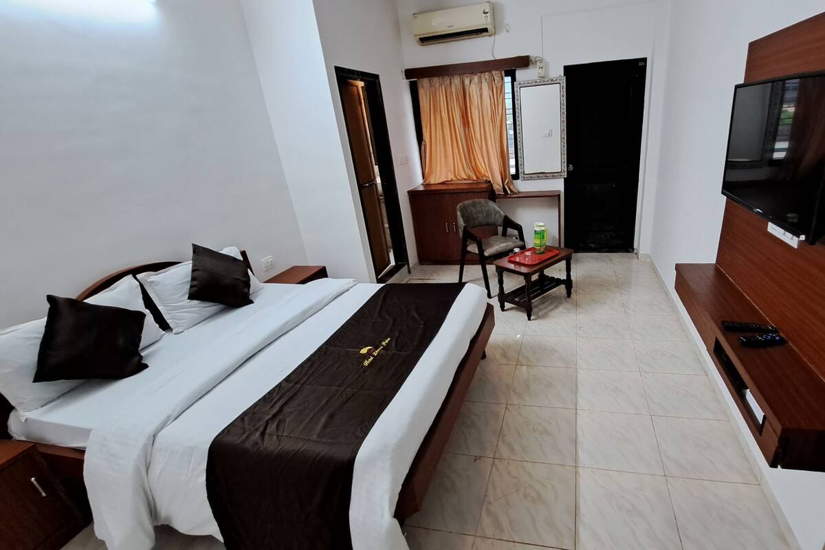 Ein Hotelzimmer mit Bett, Stuhl, kleinem Tisch, Fernseher und Kleiderschrank.