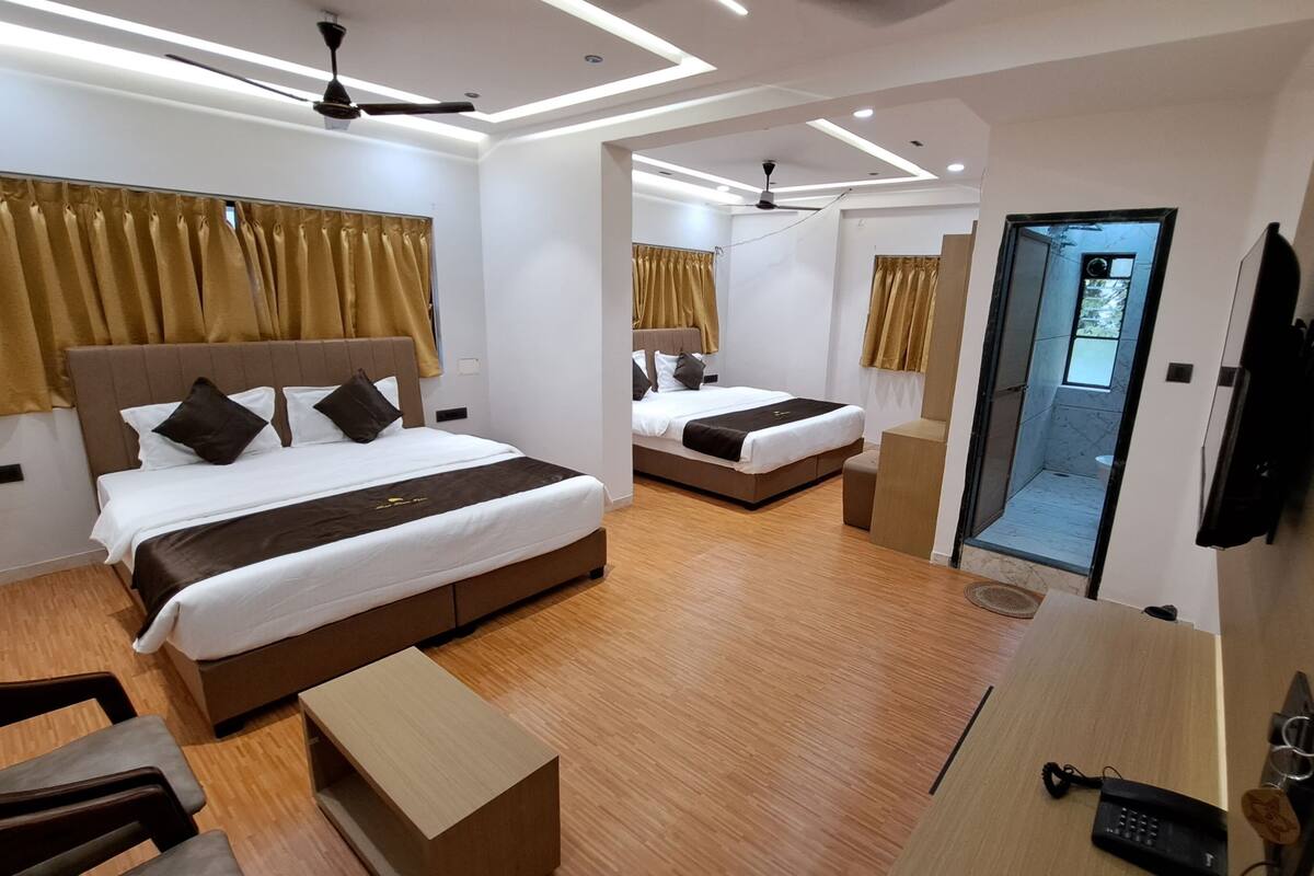 Ein modernes Hotelzimmer mit zwei Betten, Holzböden, Deckenventilatoren und einem Badezimmer mit Glastür.