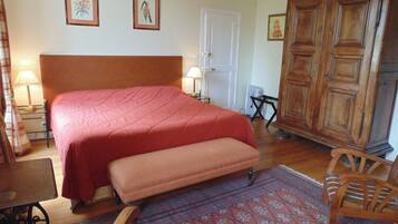Une chambre à coucher avec un grand lit, une armoire en bois, un banc et une table.