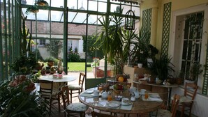 Ein Wintergarten mit einem runden Esstisch, gedeckt für das Frühstück, umgeben von Stühlen.