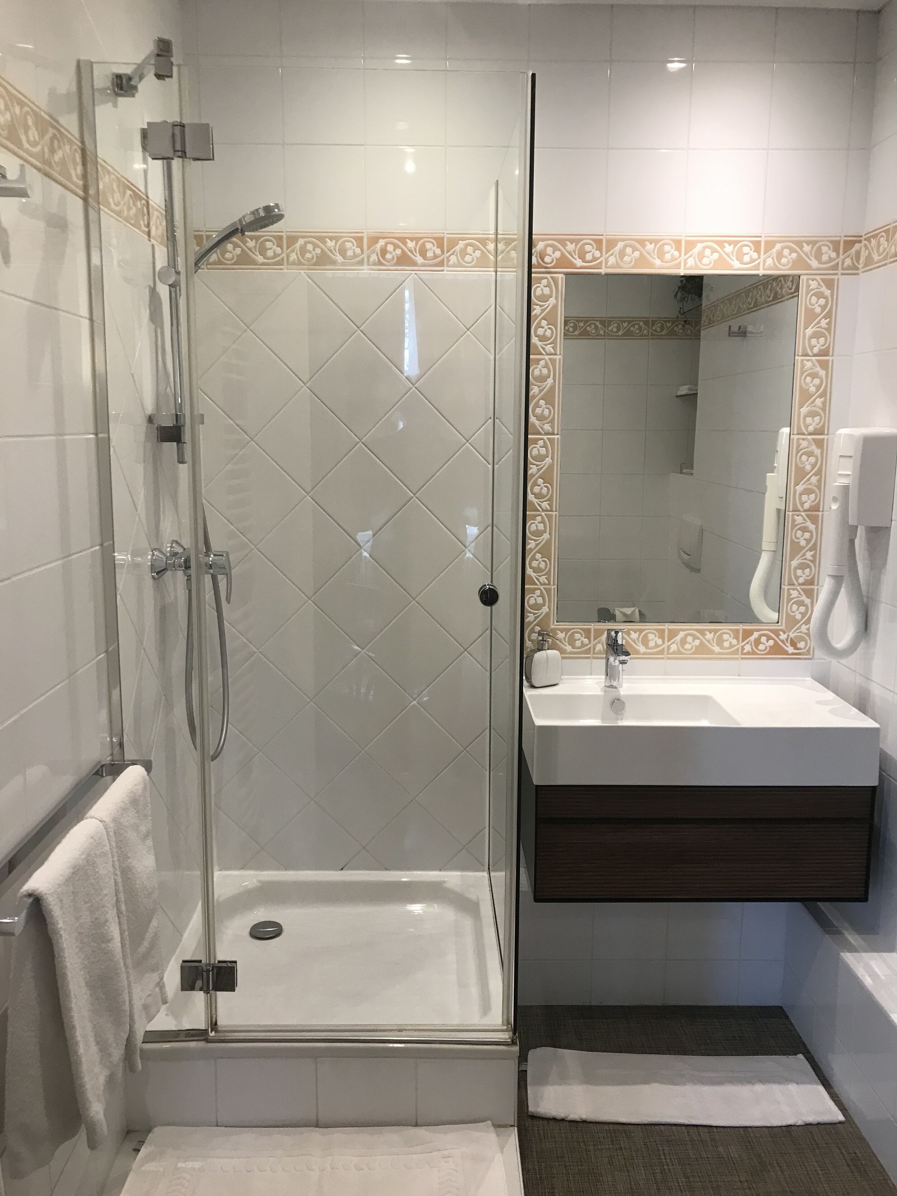 Un baño moderno con ducha de vidrio, tocador con espejo y lavabo.