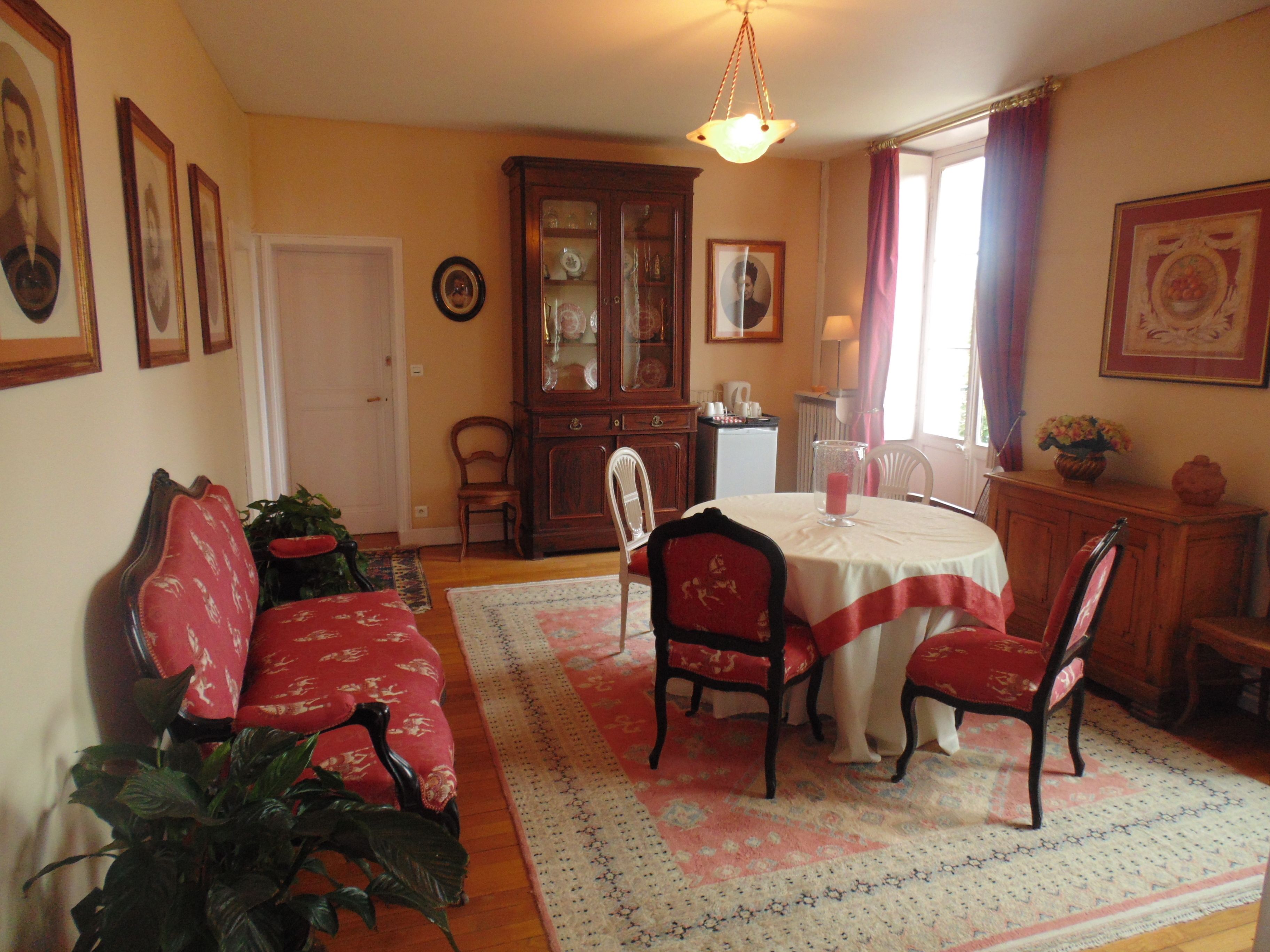 A dining room with a round table, chairs, a cabinet, and a sofa.