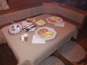 A dining table set with plates of food, salt and pepper shakers, butter, and cutlery.