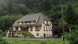 Ein zweistöckiges Gebäude mit Satteldach, einem Balkon mit Außenbestuhlung und einem Schild, das es als Restaurant kennzeichnet.