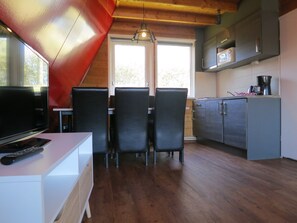 Eine kompakte Küche mit Essbereich, Holzboden und einem Fernseher auf einem weißen Tisch.