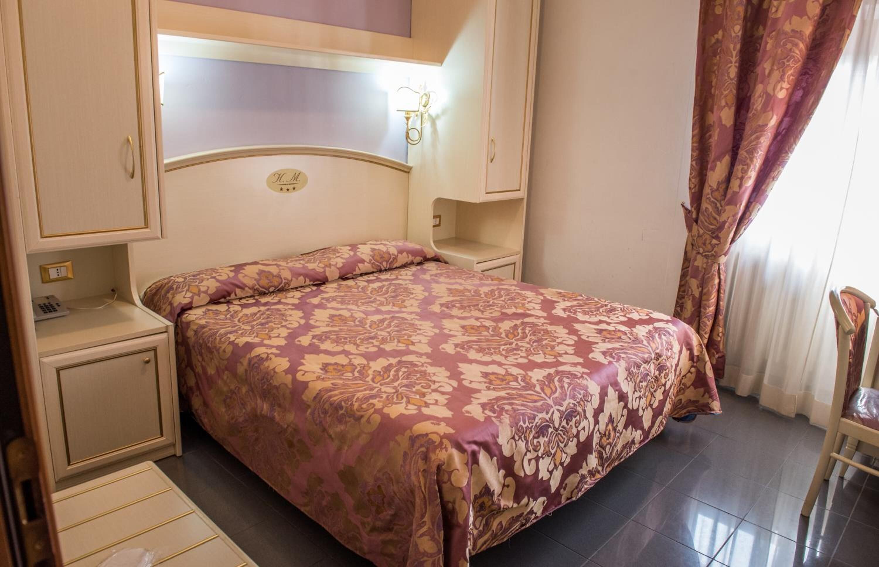 Une chambre à coucher comprenant un lit, des tables de chevet, une armoire et une chaise.