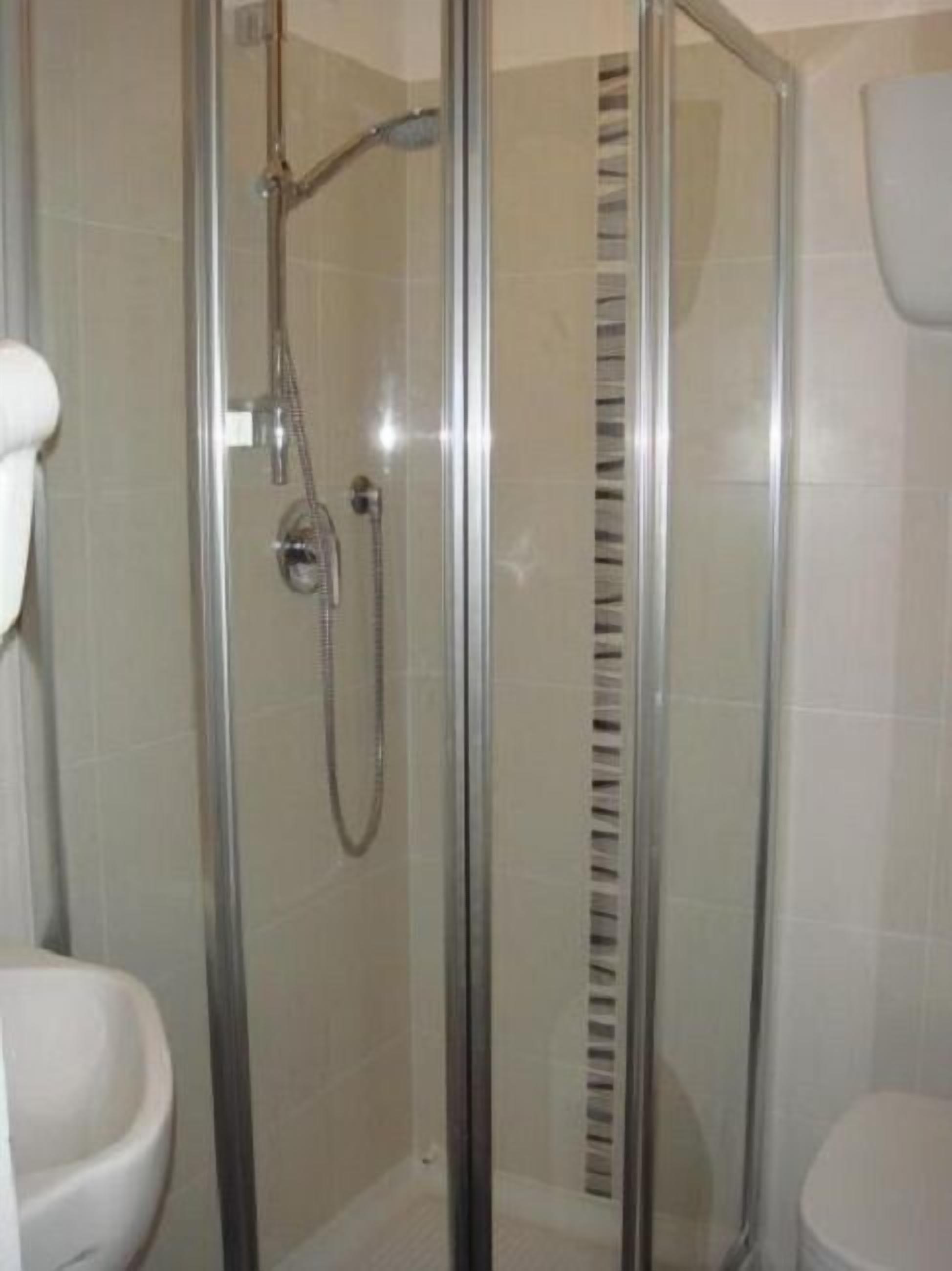 A glass-enclosed shower stall with a handheld showerhead and a wall-mounted faucet.