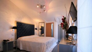 A bedroom with a large bed, bedside tables, a mirror, a desk with a lamp, and a vase with flowers. - Hotel La Meridiana (Anghiari)