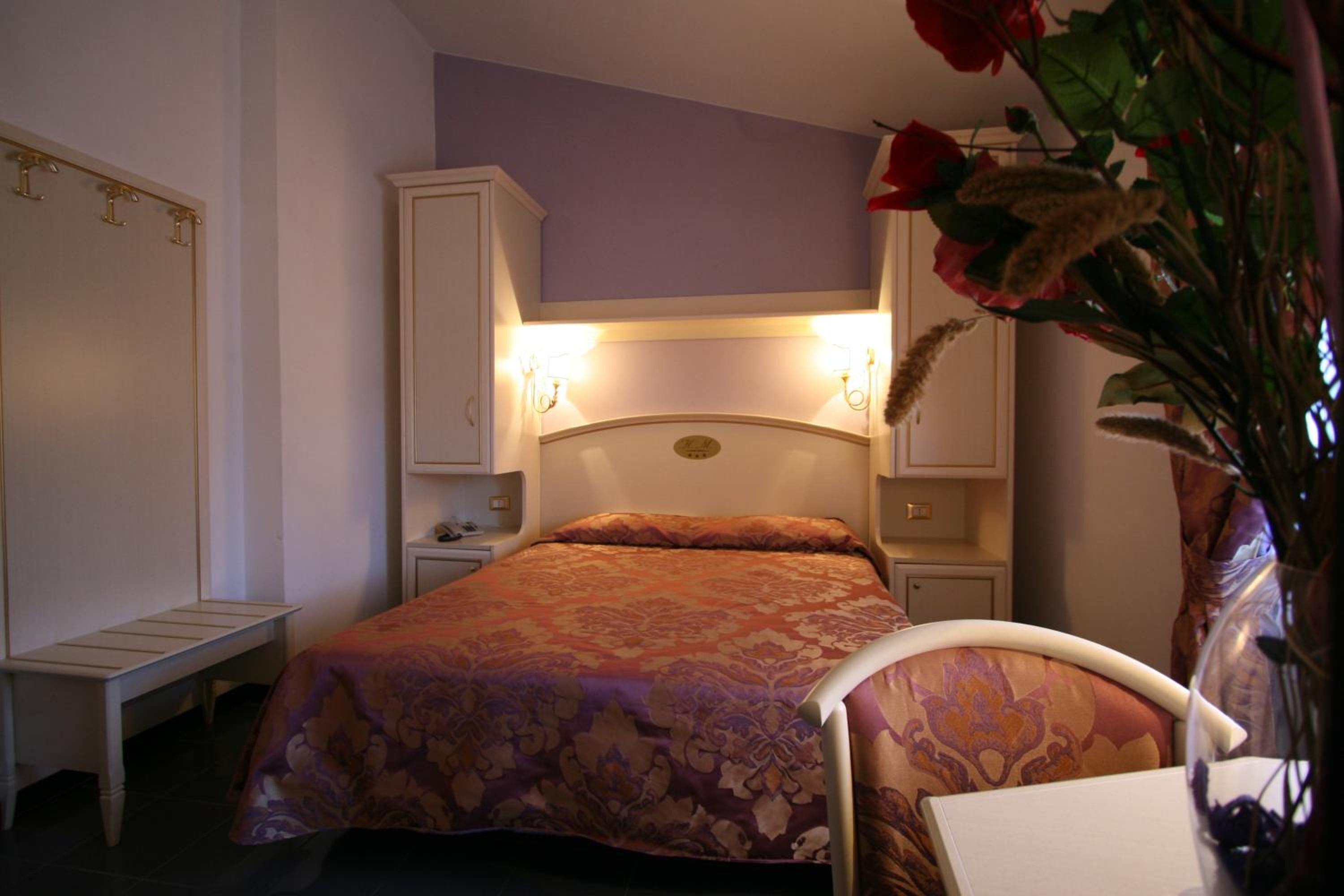 Un dormitorio con cama, mesita de noche, cómoda y banco.