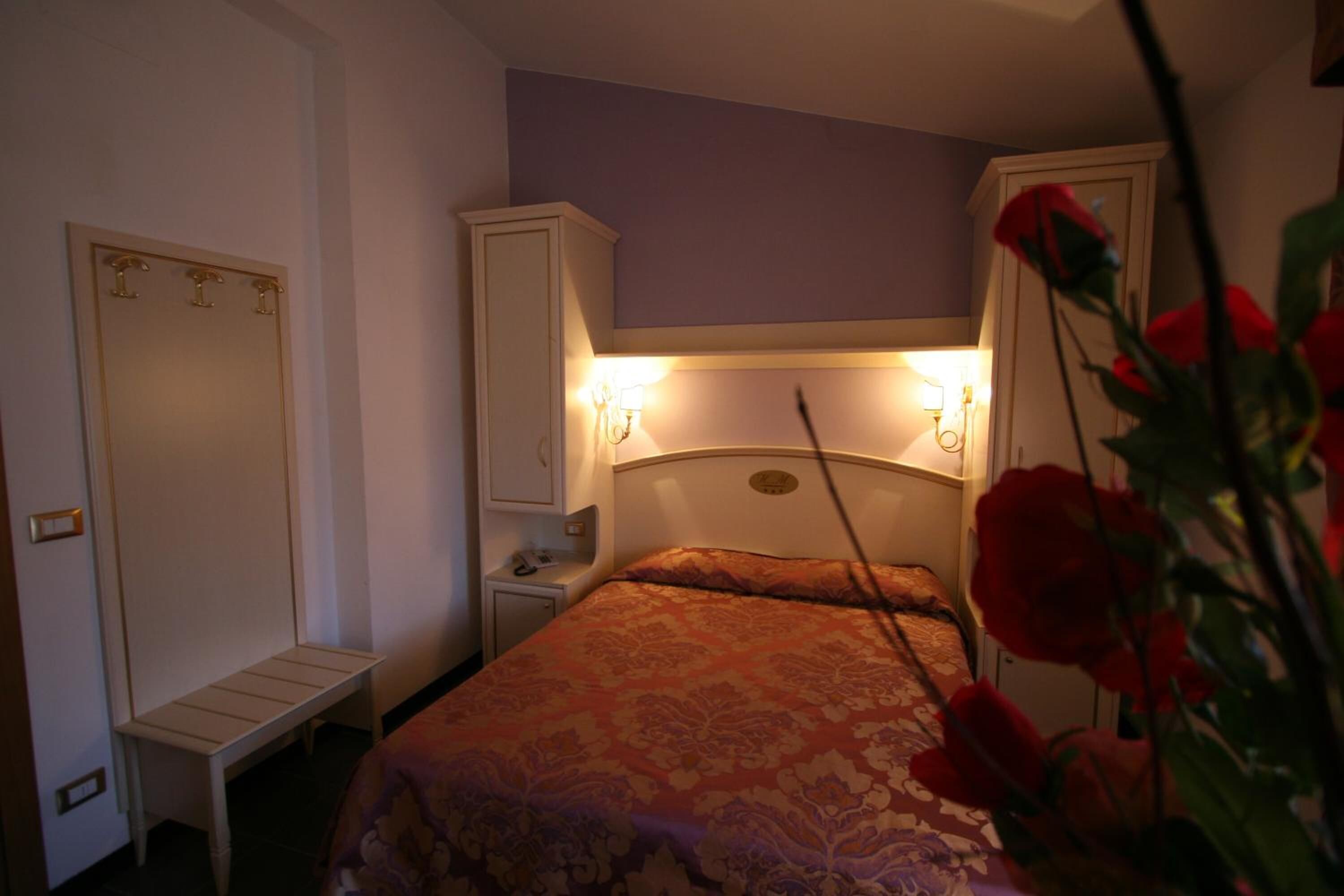A bedroom with a bed, bedside tables, a wardrobe, and a nightstand.