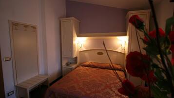 A bedroom with a bed, bedside tables, a wardrobe, and a nightstand.