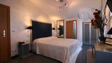 A bedroom with a bed, bedside tables, a mirror, a dresser, and a vase with flowers.