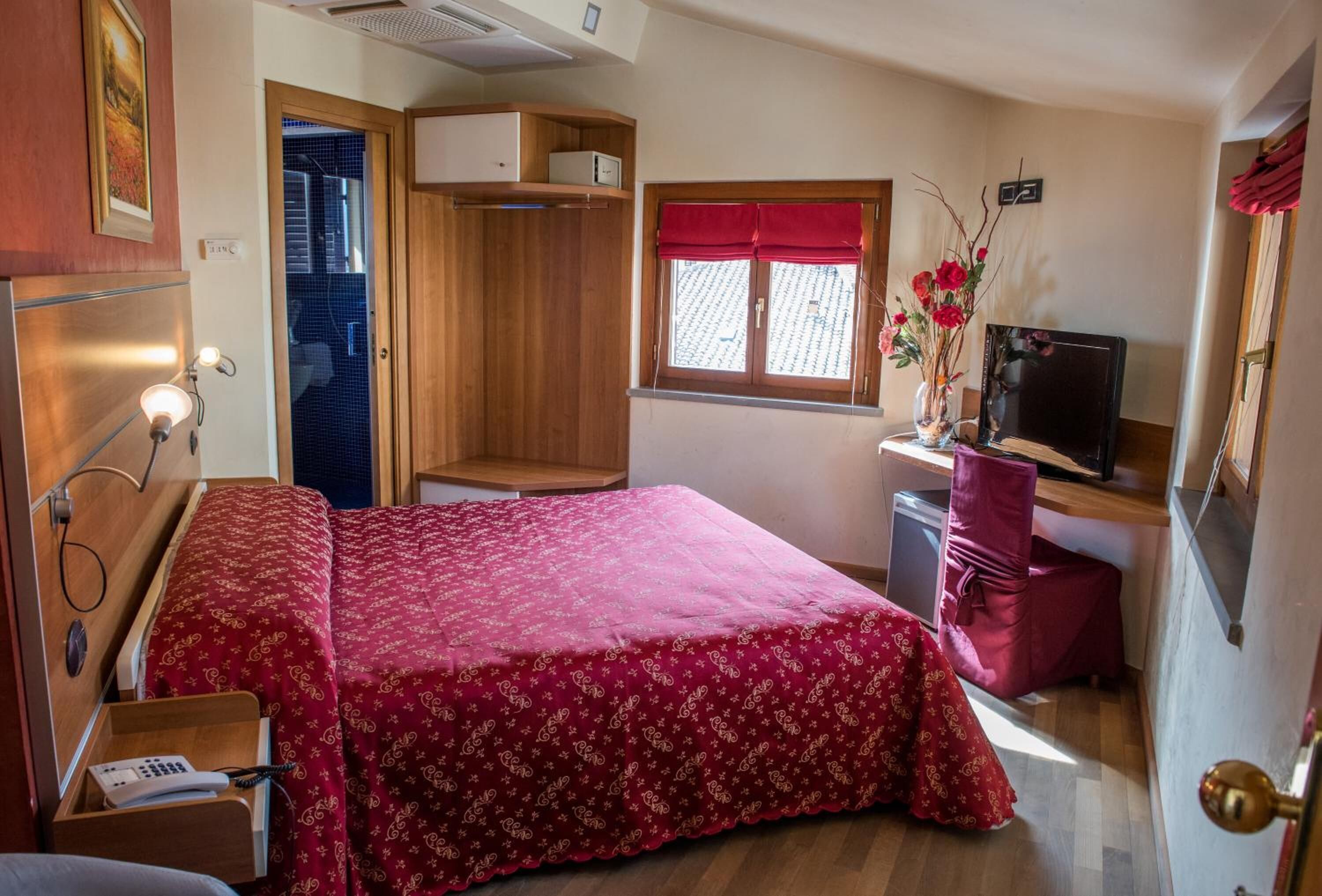 Une chambre à coucher de taille réduite, comprenant un lit, une table de chevet et un petit bureau avec une chaise.