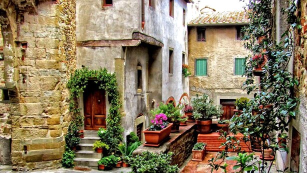 A narrow cobblestone street flanked by historic stone buildings with arched doorways and windows. - Hotel La Meridiana (Anghiari)