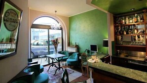 A bar area with a green wall, a computer, and a shelf with bottles. - Hotel La Meridiana (Anghiari)