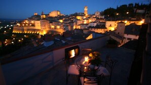 A terrace with a table and chairs, overlooking a historic town with a prominent castle and tower. - Hotel La Meridiana (Anghiari)