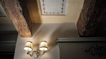 A ceiling with exposed wooden beams and a wall-mounted light fixture.