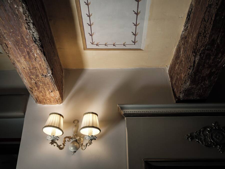 A ceiling with exposed wooden beams and a wall-mounted light fixture.
