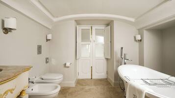 Une salle de bain comprenant des toilettes, un bidet, un meuble-lavabo et une baignoire.
