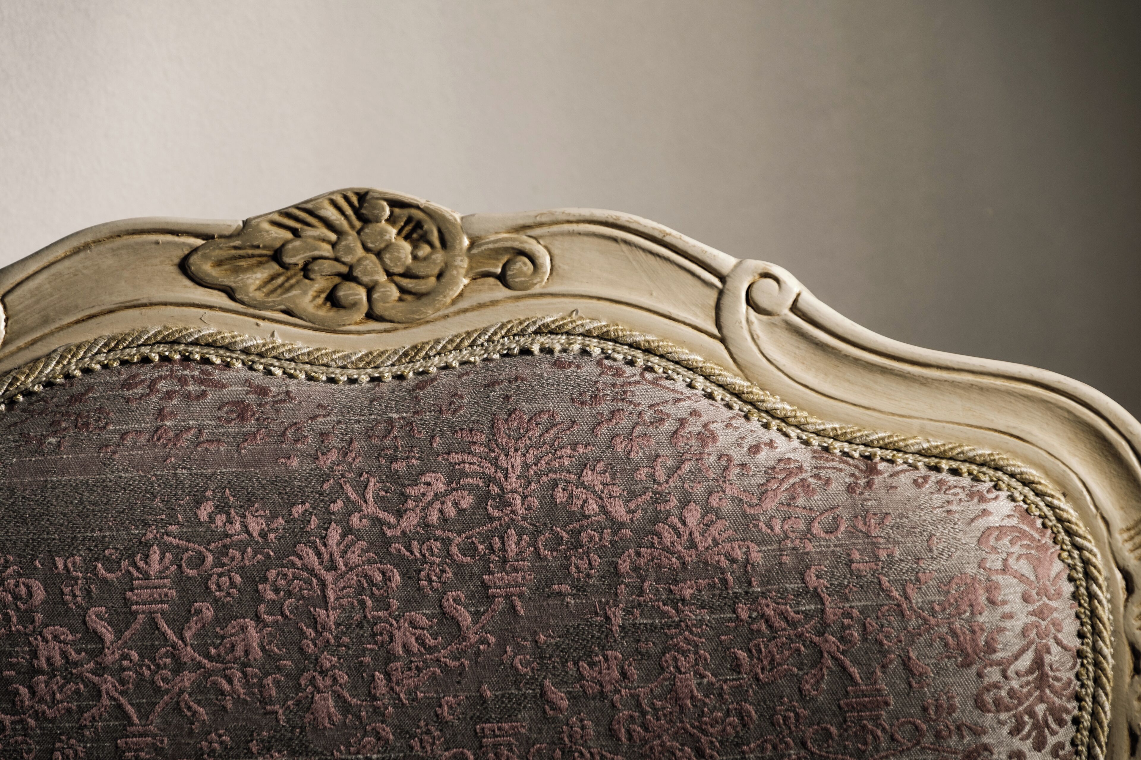 A close-up of a chair with a floral pattern upholstery and a decorative headboard.