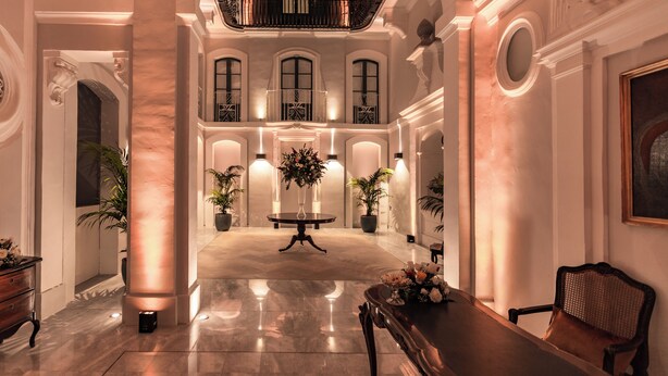 A spacious lobby with a marble floor, a central table with flowers, and a seating area with a chair. - Domus Zamittello (Valletta)