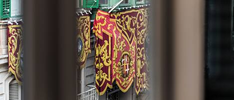 A building facade with green shutters and ornate red and gold banners.