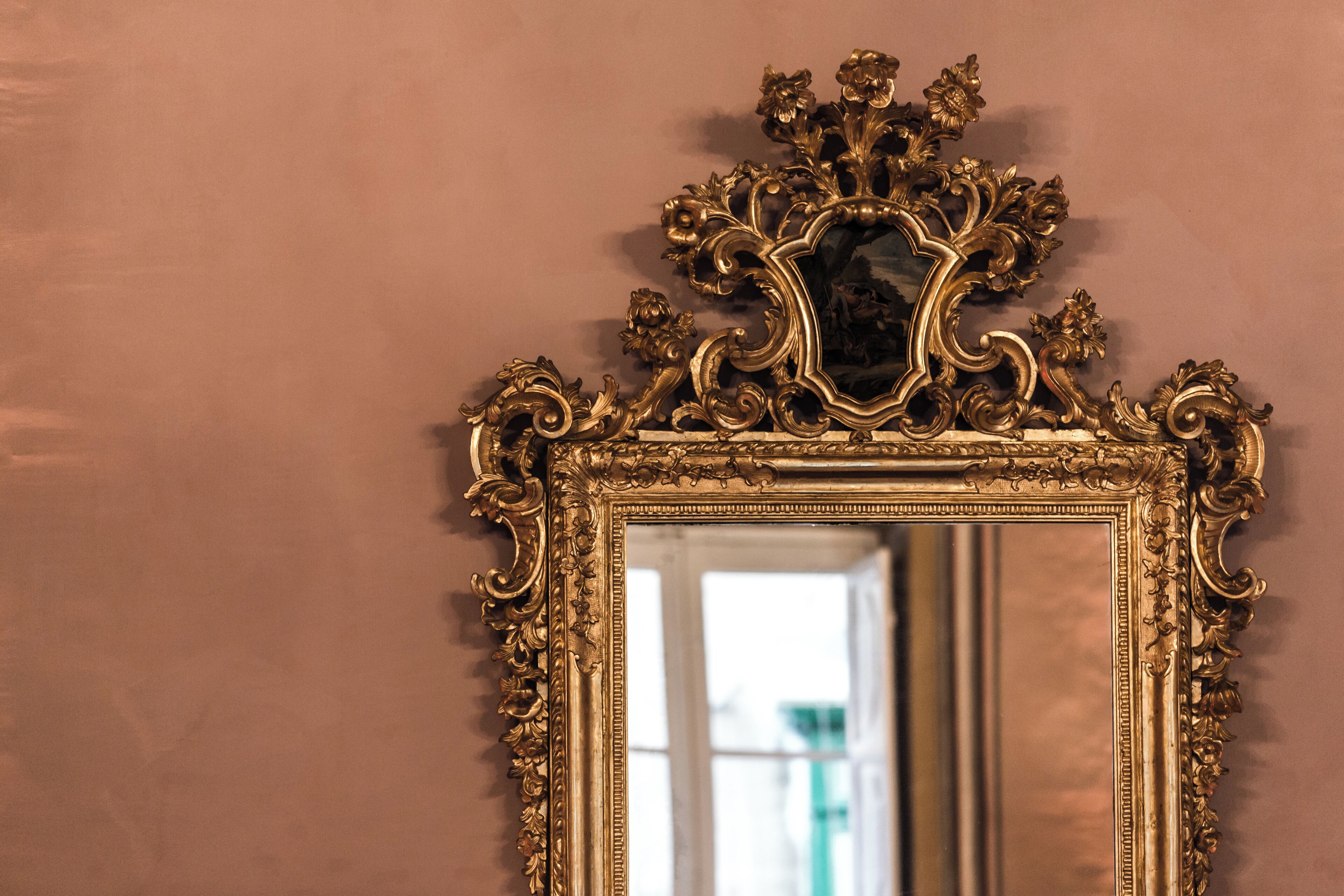 A mirror with an ornate gold frame.
