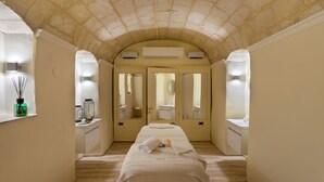 A spa room with a massage table, two mirrors, and a ceiling with a stone arch. - Domus Zamittello (Valletta)